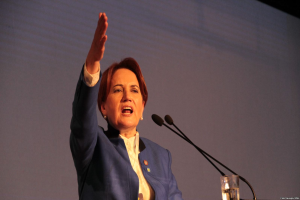 Eine Frau steht an einem Podium mit zwei Mikrofonen und einem Glas Wasser, spricht vor einem Bildschirm, wahrscheinlich zu einer Regierungsentscheidung, Frauenrechte zu verbieten.