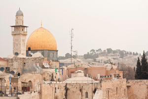 Mehrere Ziegelgebäude mit Schüssenantennen und Klimaanlagen, mit Bäumen und Himmel im Hintergrund.