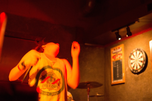 Eine Person tanzt mit einem Oberteil, wobei auf der rechten Seite Lichter zu sehen sind.