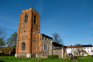 Ein grasbewachsener Bereich mit einem Pfahl, umgeben von Gebäuden und Bäumen.