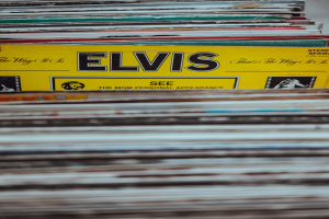 Ein ordentlicher Stapel Elvis-Presley-Platten mit lesbaren Titeln auf einem leicht unscharfen Hintergrund.