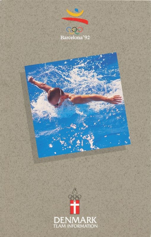 Plakat mit einem Schwimmer in blauer Badebekleidung mit ausgestreckten Armen im Wasser, unter einem blauen Himmel mit weißen Wolken, mit dem Logo und Text der Olympischen Spiele 1992 in Barcelona.