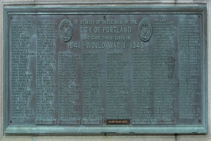 Plakette an einer Geb├Ąudewand mit der Aufschrift "Denkmal für die Stadt Portland" in fetter schwarzer Schrift, umgeben von einem dekorativen Metallrahmen.