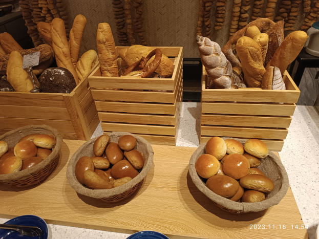 Holztisch mit Körben voller Brot, Tellern und Löffeln in einem Pariser Bäckerei-Setting.