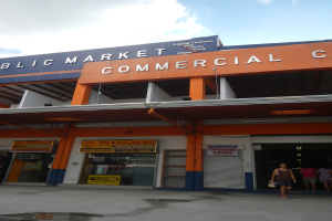 Ein öffentlicher Marktkomplex mit Menschen davor, mit Text auf dem Gebäude und einem sichtbaren Himmel oben.