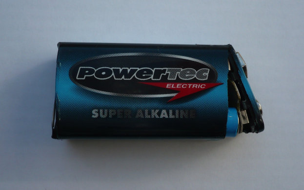 Blue Powertec Super Alkaline battery on a white surface with "Powertec" in bold lettering on its label.