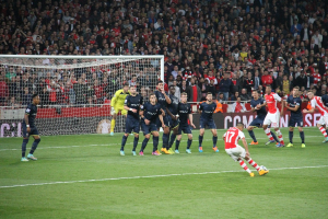 Fußballspieler auf einem Feld mit einer großen Zuschauermenge im Hintergrund.