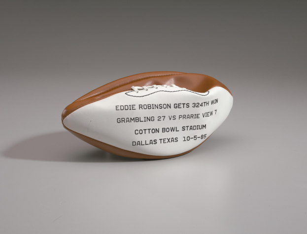 Ein brauner und weißer Fußball mit der Aufschrift "Eddie Robinson" auf einer weißen Oberfläche.