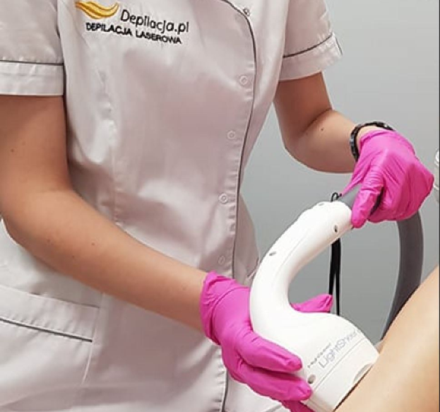 Eine Frau in einem weißen Hemd und pinken Handschuhen bedient eine weiße Laser-Haarterminationsmaschine an einer Wand.
