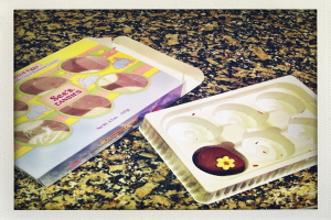 Ein Kasten mit Tierbildern und Text neben einem Tablett mit Essen, beide auf einem steinernen Sockel platziert.