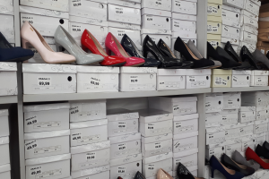 Ein Regal voller verschiedener Schuharten in Boxen, jeweils mit einem Preisschild, und Kartons auf der rechten Seite.