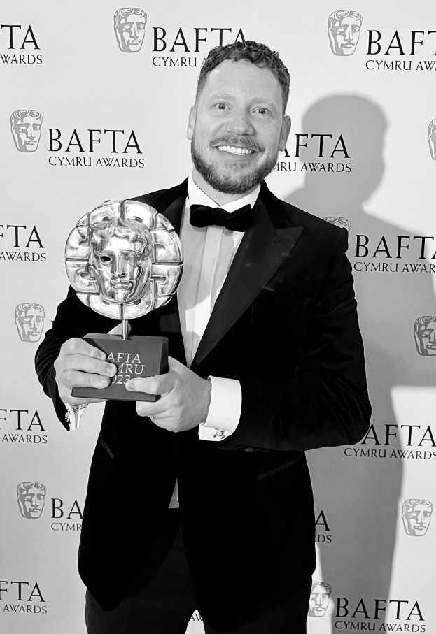 Ein Mann im Smoking mit einem BAFTA-Award, vor einer Tafel mit der Aufschrift "BAFTA Awards 2018."