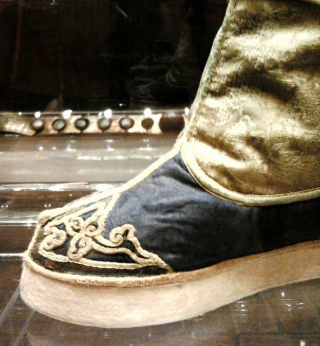 Nahaufnahme eines Schuhpaares in einer Glasvitrine auf einem dunklen Hintergrund.