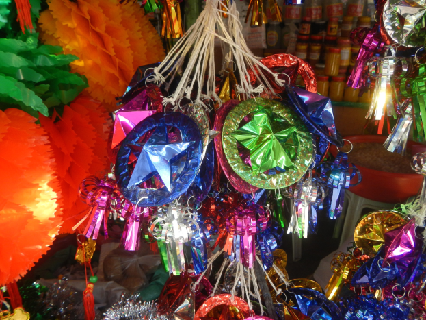 Farbenfrohe Dekorationen wie Papierlaternen und Bänder hängen von der Decke über Regalen mit Flaschen in einer festlichen Atmosphäre.