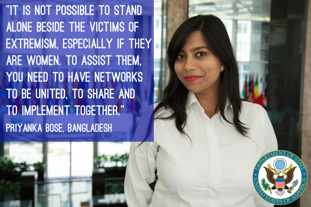 Eine Frau in einem weißen Hemd steht vor einem Gebäude mit einem Zitat über die Unterstützung von Opfern von Extremismus, mit einem Logo in der unteren rechten Ecke.