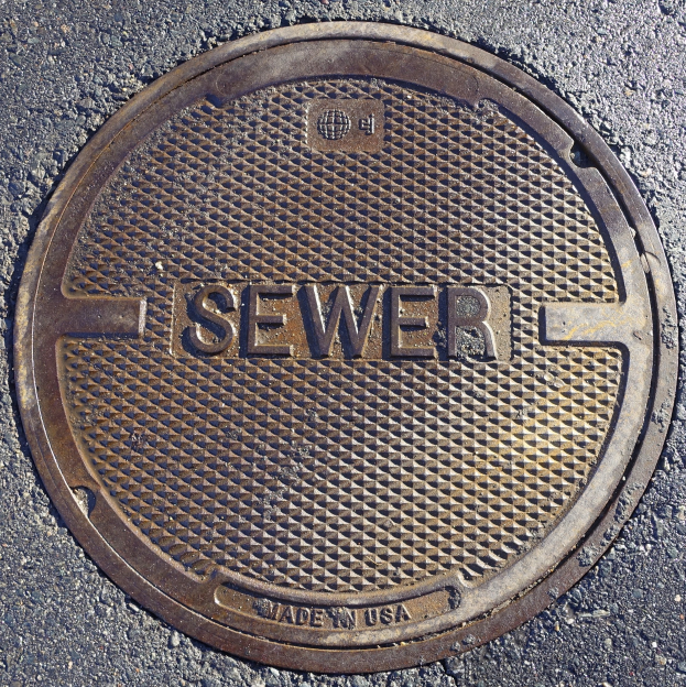 Metallschachtdeckel auf der Straße mit der Aufschrift "Kanal".