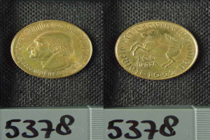 Zwei Goldmünzen aus Deutschland im Jahr 1922, jeweils mit einer Denomination von 100 Mark, die auf einer schwarzen Oberfläche mit Zahlen unten ruhen.