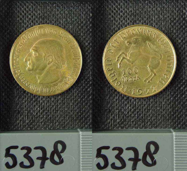 Zwei Goldmünzen aus Deutschland im Jahr 1922, jeweils mit einer Denomination von 100 Mark, die auf einer schwarzen Oberfläche mit Zahlen unten ruhen.