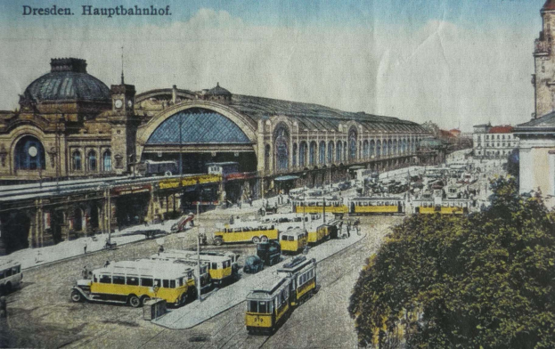 Schwarz-weiß-Postkarte des Dresdner Hauptbahnhof Bahnhofs in Dresden, Deutschland, zeigt eine belebte StraßenSzene mit Fahrzeugen, Fußgängern, Bäumen, Gebäuden und einem bewölkten Himmel.